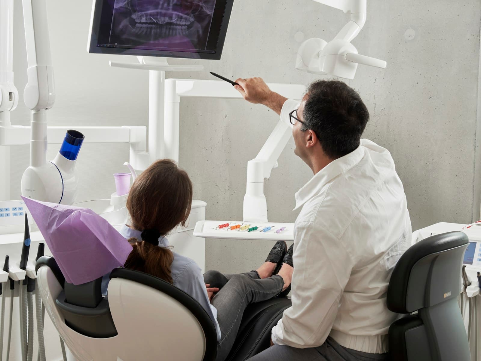 A dentist reviewing X-rays with a patient in a bright modern clinic
